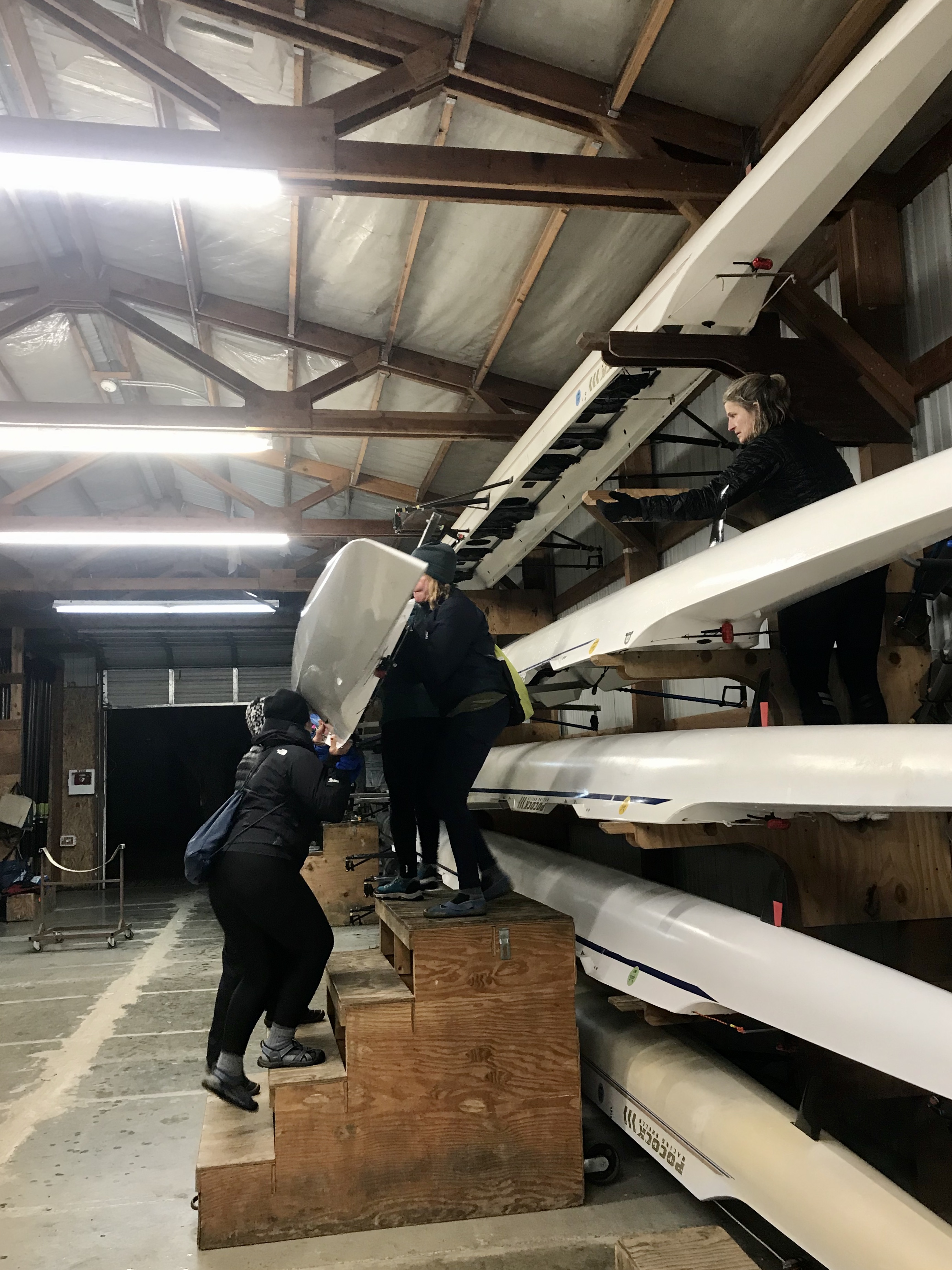 Women carrying a rowing shell down a staircase