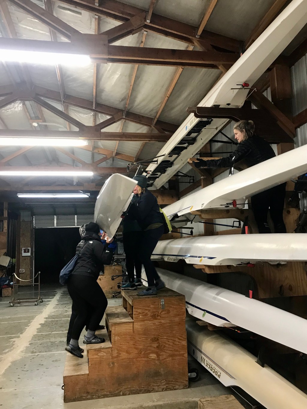 Women carrying a rowing shell down a staircase